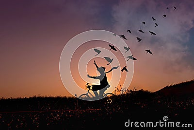 Freedom concept, Silhouette of happy person raised arms on bicycle in natural scene, Birds fly on beautiful sunrise or sunset sky Stock Photo