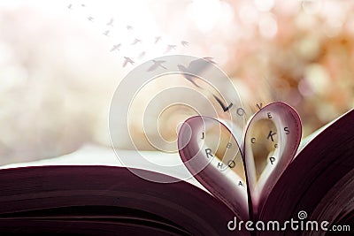 Freedom and Love Concept. Birds Flying out the Page Roll like a Heart Shape on Book Stock Photo