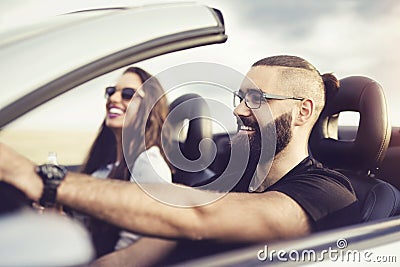 Freedom of the open road.Young Couple Driving Along Country Road In Open Top Car. Stock Photo