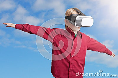 Freedom, technology and entertaiment concept. Small male child in red shirt wears VR glasses, studies possibilities of gadget, ima Stock Photo