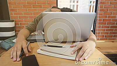 freelance Asian man worker sleeping on laptop with notebook,smart phot and pen mouse after work hard and stress. Break Digital de Stock Photo