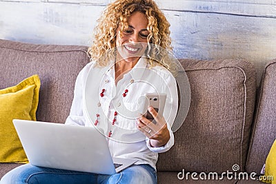 Freelance people at work at home - beautiful adult caucasian woman sit on the sofa with phone device and laptop computer working - Stock Photo