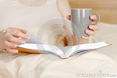Freelance work. Middle-aged woman sitting in bed with laptop and cup of coffee, stay at home Stock Photo