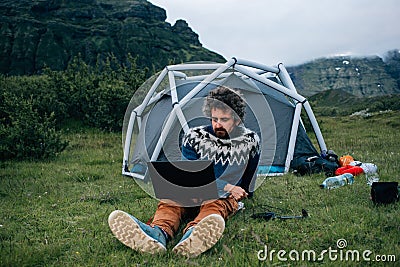 Freelance worker with laptop at camping site Stock Photo