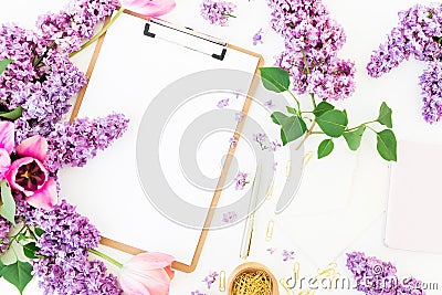 Freelancer or blogger workspace with clipboard, notebook, envelope, lilac, and tulips on white background. Flat lay, top view. Stock Photo