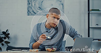 freelancer holding plastic fork and eating Stock Photo