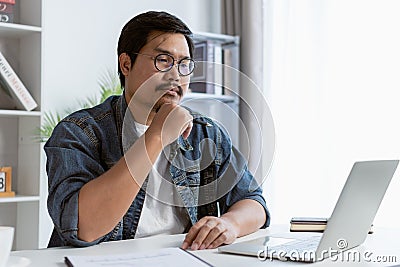 Freelancer is thinking idea or trying to solve a problem. A man is working on his laptop. Stock Photo