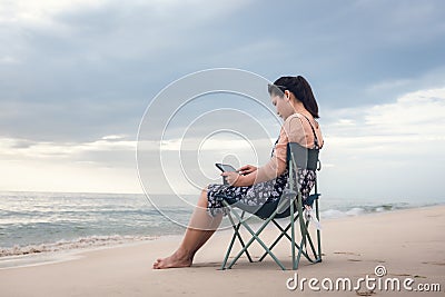 Freelancer Woman is Working on Tablet While Travel Vacation Trip at The Beach, Smart Woman is Using Tablet for Communication and Stock Photo
