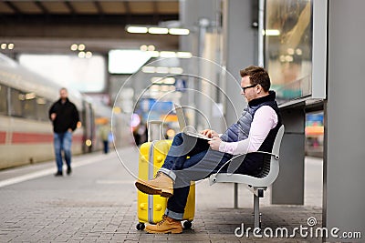 Freelancer working with a laptop in a train station while is waiting for transport Stock Photo