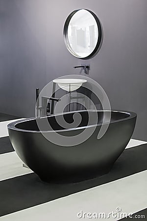 Freestanding black bathtub, stylish minimalist black and white loft style bathroom. Bath, washstand, mirror on the wall Stock Photo