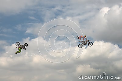 Freestyle Motocross trick of two motorcyclists on background of the blue cloud sky. Extreme sport. German-Stuntdays, Zerbst - 2017 Editorial Stock Photo