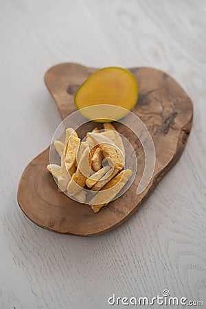 Freeze-dried mango with fresh one on olive wood board Stock Photo