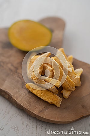 Freeze-dried mango with fresh one on olive wood board Stock Photo