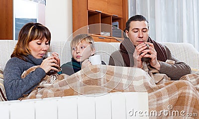 Freezing family of three warming near warm radiator Stock Photo