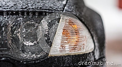 Freezing rain ice coated car. Headlight and signal light on black car covered in freezing rain. Bad driving weather. Stock Photo