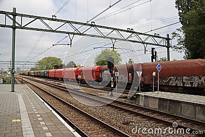 Freight locomotive with cargo wagons along platform of train station Den Haag Laan van NOI Editorial Stock Photo