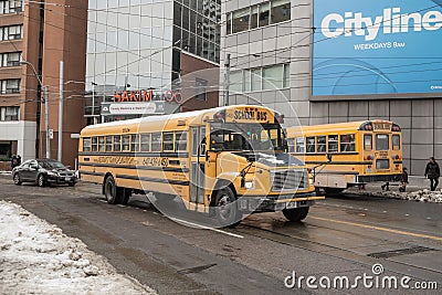 Freightliner FS 65 school bus on service in a residential part of downtown Toronto, another yellow school bus can be seen Editorial Stock Photo