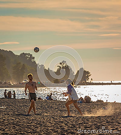 Freinds playing beach volleyball having fun in sporty active life. Young people playing volleyball on beach at sunset Editorial Stock Photo