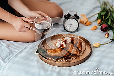 French breakfast in bed with coffee and croissants. Healthy breakfast served on a tray on bed with alarm clock. Coffee Stock Photo