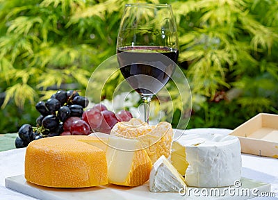 French cheeses collection, yellow Riche de Saveurs, Vieux Pane and Le peche des bons peres cheeses served with glass of red port Stock Photo