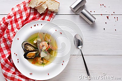 French seafood soup with white fish, shrimps and mussels in plate at wooden background Stock Photo