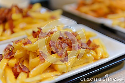 French fries and cheese with bacon on top in white bowl Stock Photo