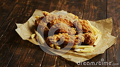 French fries and chicken wings on parchment Stock Photo