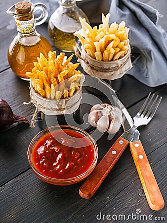 French fries in a metal mug with tomato sauce on a rustic background. Portion potato fries. Tasty Snack from fast food. Fork, Stock Photo