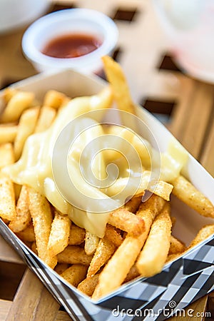 French Fries on Toping Cheese in Paper Box. Stock Photo