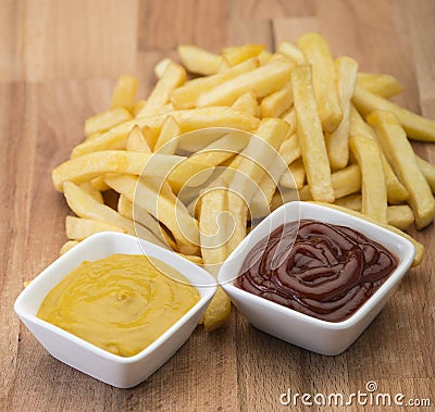 French fries on wooden board with catchup & mustard sauce Stock Photo