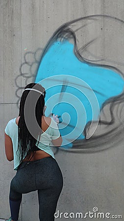 Graffiti artist spray paints a piece on a wall Editorial Stock Photo