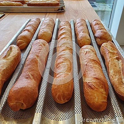 Fresch gold baquettes on baking tray in a bakery, food and bakery concept Stock Photo