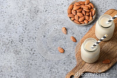 Fresh almond milk in glass bottle and almonds around on beige. View from above Stock Photo