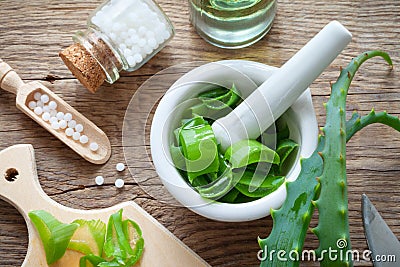 Fresh aloe vera leaves, mortar full of chopped aloe and bottle of homeopathy globules. Stock Photo