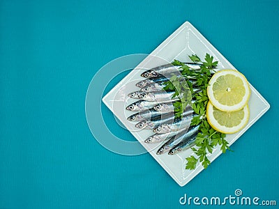 Fresh anchovies in a plate on a blue background Stock Photo