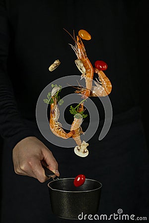 Fresh appetizing shrimp fall into a black pan on a dark background Stock Photo