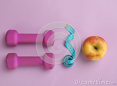 Fresh apple, measuring tape and dumbbells Stock Photo