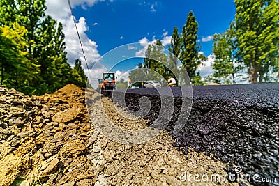 Fresh asphalt on highway construction site. Industrial pavement machine laying. Stock Photo