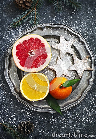 Fresh assorted citrus fruits and Christmas cookies on plate Stock Photo