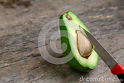 Fresh Avocado cut in half on wooden board with knife background Stock Photo