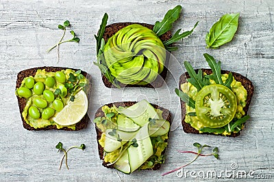 Fresh avocado toasts with different toppings. Healthy vegetarian breakfast with rye wholegrain sandwiches. Stock Photo