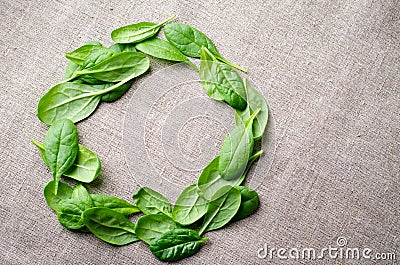 Fresh Baby spinach leaves on sackcloth background. Top view with copy space, round circle frame. Healthy, Ecology Stock Photo