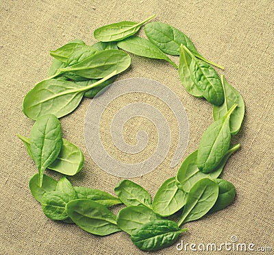 Fresh Baby spinach leaves on sackcloth background. Top view with copy space, round circle frame. Love, Healthy, Ecology Stock Photo