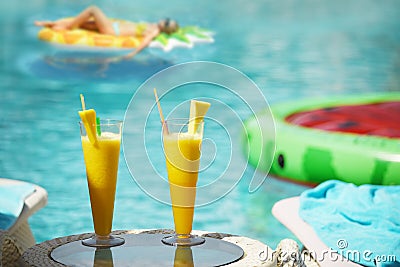 Fresh bass citrus juices. Girl on an air mattress in the background in the pool water. The atmosphere of a holiday by the pool. Stock Photo