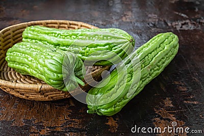 Fresh bitter gourd in a basket on wooden table Stock Photo