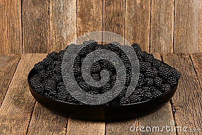 Fresh blackberry in plactic bowl on dark wood background Stock Photo