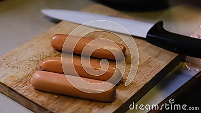 Fresh boiled sausages on wooden cutting board and knife background Stock Photo