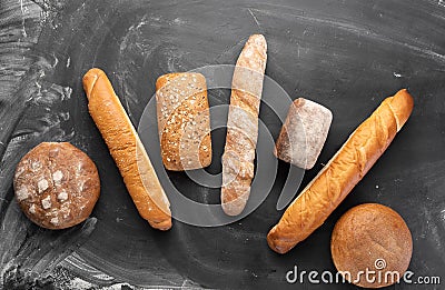 Fresh bread on a black background, top view. Homemade fresh pastries of various loaves of wheat and rye bread close-up. Stock Photo