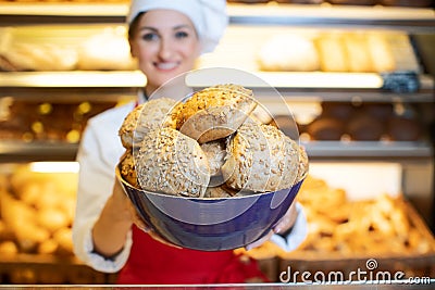 Fresh bread presented by an attractive young sales woman in bakery Stock Photo