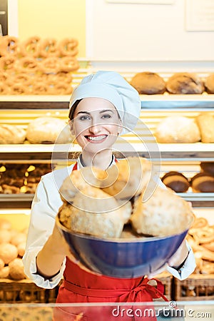 Fresh bread presented by an attractive young sales woman in bakery Stock Photo